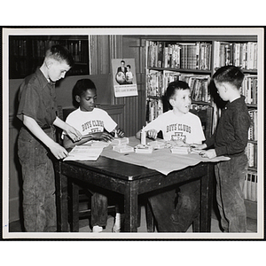 Four boys sit and stand around a table, working on projects for their arts and crafts class at the Boys' Clubs of Boston