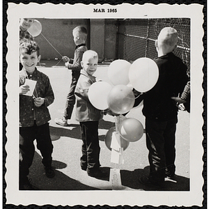 Boys stand with ballons during a ballon raising at a carnival