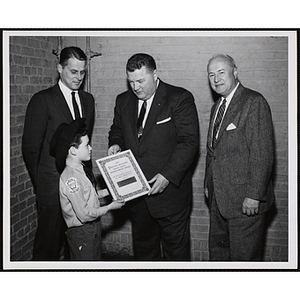 Vice-President of the Boys' Club of Boston Richard Harte, Jr. (left) and Executive Director of Boys' Club of Boston Arthur T. Burger (right) pose with an identified man, presenting a member of the Bunker Hillbillies with the "The Parents Magazine Youth Group Achievement Award for Outstanding Service to the Community"