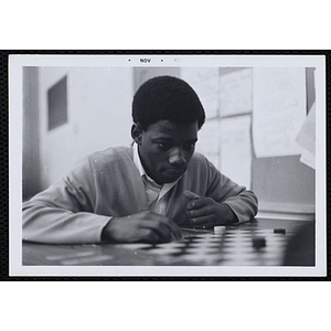 A boy contemplates a move on a checker board