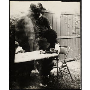 A boy plays cards outdoors as a man looks on