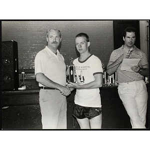 A man shakes hands with a teenage boy as they pose with a trophy during the Battle of Bunker Hill Road Race