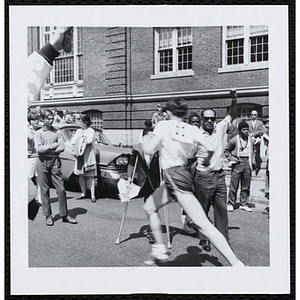 A runner strides under the finish line held aloft by two men during the Roxbury Road Race