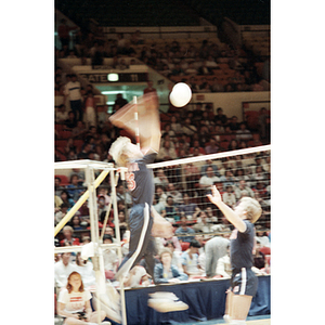 United States Men's Volleyball Team member jumps to hit a ball across the net, while his teammate stands to his right