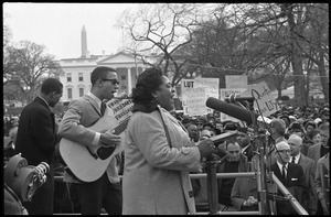 Fannie Lou Hamer singing at the microphones, accompanied by a guitarist, during a civil rights demonstration, in front of the White House on Lafayette Square
