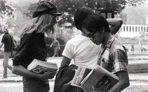 Free Spirit Press crew member distributing the magazine in front of the UMass Amherst Student Union Building, Campus Pond and Morrill Hall in the background