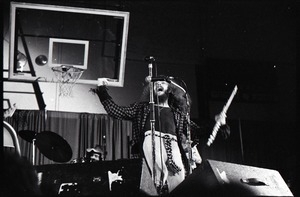 Jethro Tull in concert at the Springfield Civic Center: Ian Anderson at microphone with flute (basketball hoop in background)