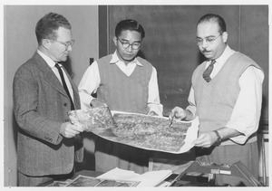 Harold Theodore Uhr Smith standing with two unidentified men looking at map