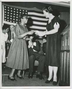 Unidentified woman handing gift to a client at graduation exercises