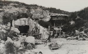 View of machine guns and rifles leaning against the entrance to an abandoned German bunker