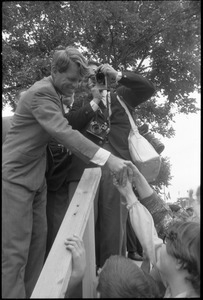 Robert F. Kennedy shaking hands with the crowd from atop the stage while stumping for Democratic candidates in the northern Midwest
