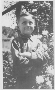 Edward Snow Willis standing with arms folded outside amongst flowers