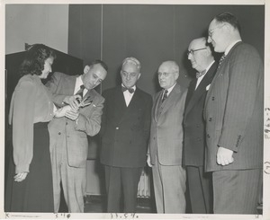 Four men watch as another man fits a woman with a prosthetic arm