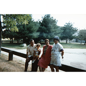 Four people pose by a fence at an outdoor picnic event