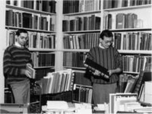 Two men examine books in the west office of the Chapin Library