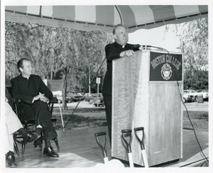 Robsham Theatre exterior: groundbreaking, J. Donald Monan listening to Joseph M. Larkin speak at podium