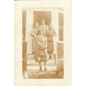 Four women in coats stand on the steps