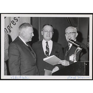 From left to right, Robert C. Cole, William J. Lynch, and A. Boyd Hinds, standing at the podium during a Boys' Clubs of America event