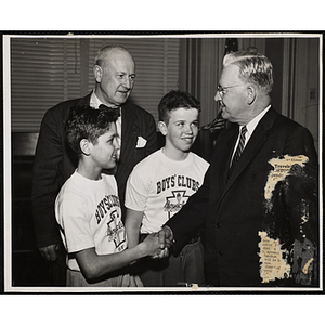 Mayor John B. Hynes shakes hands with Thomas Malomo as Executive Director of Boys' Clubs of Boston Arthur T. Burger and Joe Quinn look on