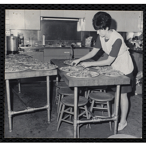A woman prepares plates of food in a kitchen for a Dad's Club/Mother's Club banquet