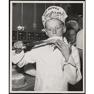 A member of the Tom Pappas Chefs' Club licks frosting from a spatula in a Brandeis University kitchen