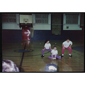 Three girls performing a dance routine in the gymnasium