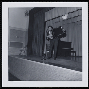 A man plays an accordion on stage at a Christmas party