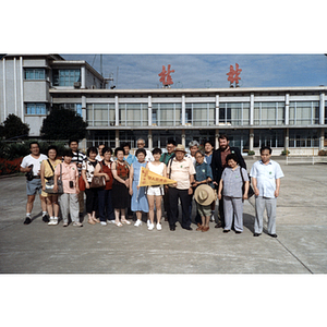 Men and women stand in front of a low concrete building