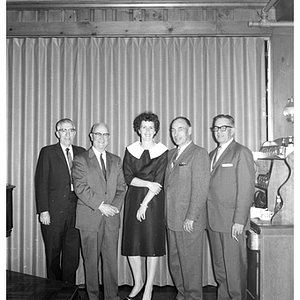 A woman and four men pose together