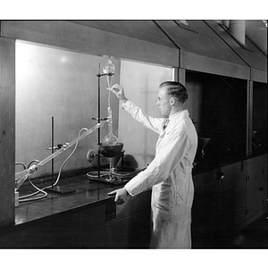 Student conducting chemistry experiment under a fume hood