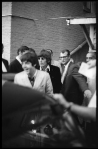 Paul McCartney and George Harrison entering a limousine (Brian Epstein in the background)