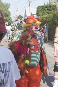 Parade marcher dressed as a clown with a monkey puppet : Provincetown Carnival parade