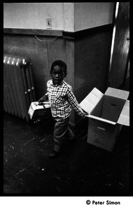 Young boy with a cardboard box and Peanuts lunch pail, Liberation School