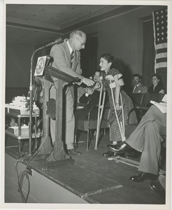 Unidentified staff member handing prize to client on crutches at Institute Day