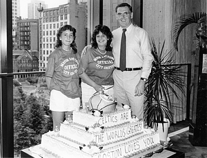 Mayor Raymond L. Flynn posing with two unidentified Mayor Ray Flynn Official City Greeters behind a Boston Celtics cake