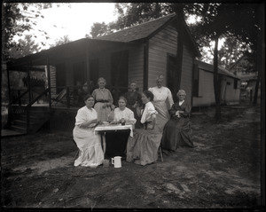 Nurses seated at a table in front of a cottage