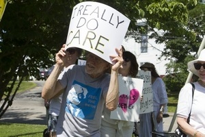 Pro-immigration protester shielding his eyes from the sun with a sign reading 'I really do care': taken at the 'Families Belong Together' protest against the Trump administration’s immigration policies