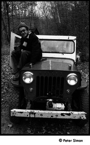 Raymond Mungo seated on the hood of a Willys jeep, Packer Corners Commune