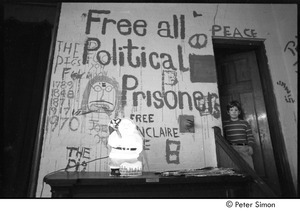 Boy standing in doorway by mural that reads, 'free all political prisoners'