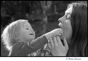 Young child putting her hand in the mouth of a woman
