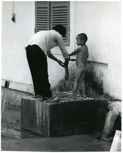 Woman bathing child outdoors