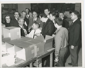 Seated man at desk of boxes addressing French delegation to ICD