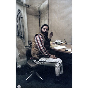Construction worker at a desk with an open notebook and calculator before him.