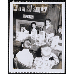 Boys sit a table with a book display in a library