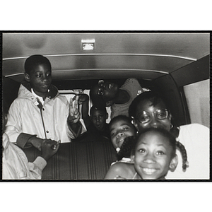 A group of children and an adult smile in a van