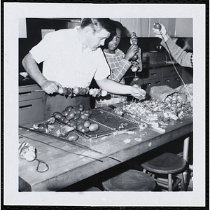 A man and a boy skewer kabobs in a kitchen