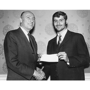 A man hands a check to a student