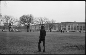 Lone man with a balloon walking across the edge of the National Mall during the Counter-inaugural demonstrations, 1969, and march against the War in Vietnam