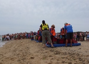 International Fund for Animal Welfare volunteers begin to lift dolphins off their mats to carry them to the water, with crowd looking on