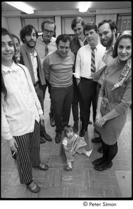 Staff of Cambridge Phoenix posing with a baby: Jean Grillo (left) ,Elliot Blinder (3rd from left), Robert Ventola (bending over), Jeffrey Tarter (2nd from right)